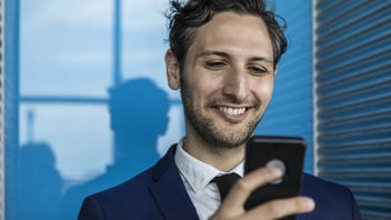 Smiling young business man holding a smartphone